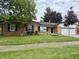 Charming single-story home with a brick exterior, manicured lawn, and mature trees enhancing its curb appeal at 7764 Hollybrook Ln, Southport, IN 46227