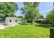 Spacious backyard with green lawn, mature trees, detached garage, and partial fence at 7849 E 49Th St, Indianapolis, IN 46226