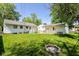 Large backyard featuring lush green grass, mature trees, fire pit, and detached garage at 7849 E 49Th St, Indianapolis, IN 46226