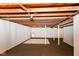 Unfinished basement features exposed wooden beams and white support beams on neutral carpeting at 7849 E 49Th St, Indianapolis, IN 46226