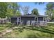 View of backyard with mature trees and the exterior of the home, which features vinyl siding and newer windows at 807 Vasbinder Dr, Chesterfield, IN 46017