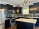 Stylish kitchen featuring dark cabinets, stainless steel appliances, a central island, and a modern backsplash at 837 Sommersweet Run, Greenwood, IN 46143