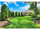 Large backyard showcases lush green grass, mature landscaping, and a charming stone retaining wall at 8905 Stonebriar Dr, Indianapolis, IN 46259
