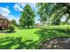 Spacious backyard with expansive lawn, mature trees, a wooden deck, and an iron fence, perfect for outdoor activities at 8905 Stonebriar Dr, Indianapolis, IN 46259