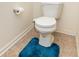 Close-up of a toilet on the tile floor with a plush, blue rug at 928 Cherry Tree Ln, Greenwood, IN 46143