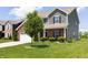 Two-story home featuring green siding, brick accents, an attached two car garage and a well-manicured front yard at 928 Cherry Tree Ln, Greenwood, IN 46143