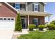 Charming front porch with brick accents, manicured bushes, and a welcoming entrance with a black front door at 928 Cherry Tree Ln, Greenwood, IN 46143