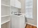 Efficient laundry room featuring front-load washer and dryer, upper cabinets, and wood floors at 9760 Innisbrook Blvd, Carmel, IN 46032
