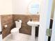 Stylish half bathroom with wood paneled walls, white sink, and toilet and round mirror at 10773 Brighton Knoll S Pkwy, Noblesville, IN 46060