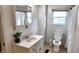 Modest bathroom featuring a toilet, sink, mirror, tiled walls, and a window offering natural light at 1148 N Pershing Ave, Indianapolis, IN 46222
