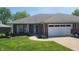 Inviting brick home featuring an attached garage, well-maintained lawn, and cozy front porch at 123 Old Farm Rd, Danville, IN 46122