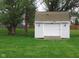Well-maintained backyard shed with a roll-up door, surrounded by lush greenery and mature trees at 12681 E 79Th St, Indianapolis, IN 46236