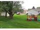 Lush backyard with a playset, mature trees, and a parked car in the driveway at 12681 E 79Th St, Indianapolis, IN 46236