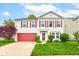 Charming two-story home with a red door, red garage door and red shutters with landscaped front yard and a beautiful tree at 13295 Patriotic Way, Fishers, IN 46037