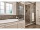 Elegant bathroom features a soaking tub, walk-in shower with river rock floor, and neutral tiling at 13309 Carmichael Ln, Carmel, IN 46074