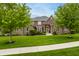 Beautiful brick home featuring a well-manicured lawn, mature trees, and inviting front entrance at 13309 Carmichael Ln, Carmel, IN 46074