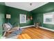 Bedroom with hardwood floors, green walls, two windows, and acoustic guitars at 2336 Sycamore St, Columbus, IN 47201