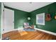 Small bedroom with hardwood floors, green walls, acoustic guitar, and minimal décor at 2336 Sycamore St, Columbus, IN 47201