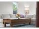 Living room featuring a white sectional sofa, rustic wooden table, a blue rug, and a sunlit window at 2336 Sycamore St, Columbus, IN 47201