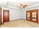 Bedroom featuring a ceiling fan, neutral carpet, and double doors to a sunroom at 3126 Oakmont Dr, Lapel, IN 46051