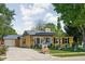 Quaint yellow home with blue door, flowers, detached garage and a paved driveway at 3433 Brewer Dr, Indianapolis, IN 46222