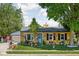 Charming yellow home with beautifully landscaped front yard, blue door, and detached garage at 3433 Brewer Dr, Indianapolis, IN 46222
