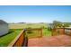 Wooden deck with railing offering scenic views of adjacent green field and clear blue sky, pool and neighborhood shed at 40 Clear Spring Ln, Trafalgar, IN 46181