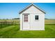 Well-maintained white shed with a classic design and window, set on a lush green lawn under a clear blue sky at 40 Clear Spring Ln, Trafalgar, IN 46181