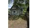 Side view of a quaint two-story home with green siding, surrounded by lush trees and greenery at 44 S Butler Ave, Indianapolis, IN 46219