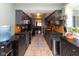 Galley kitchen features dark cabinetry, granite counters, tile backsplash, and view to dining area at 5077 Vantage Point Rd # 1 Wm-5-1, Avon, IN 46123