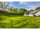 Wide open grassy backyard with mature trees, a wooden fence, and the side of the home at 51 Glasgow Ln, Noblesville, IN 46060