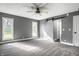 Large bedroom with a ceiling fan, plush carpet, two windows, and a white sliding barn door at 51 Glasgow Ln, Noblesville, IN 46060