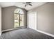 Bright bedroom featuring plush carpet, a ceiling fan, and a large window overlooking the yard at 51 Glasgow Ln, Noblesville, IN 46060