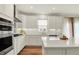Kitchen displays white cabinets, stainless steel appliances, hardwood floors and large island with quartz countertop at 5366 Laurel Crest Run, Noblesville, IN 46062