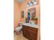 Cozy bathroom with a pedestal sink, toilet, and wall-mounted mirror with a framed picture on a peach-colored wall at 5920 Crooked Creek E Dr, Martinsville, IN 46151