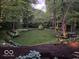 Serene backyard featuring a lush lawn, garden beds, and mature trees, creating a peaceful retreat at 5958 Cape Cod Ct, Indianapolis, IN 46250