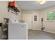 Well-equipped laundry room with gray tile flooring, modern washer and dryer, and storage shelving at 5958 Cape Cod Ct, Indianapolis, IN 46250