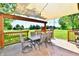 Patio dining area featuring an overhead shade, stone floor, and a view of the spacious, well-maintained yard at 5979 E Oak Hl Dr, Plainfield, IN 46168
