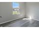 This bedroom has neutral gray walls, light wood-look flooring and a sunlit window looking out onto the neighborhood at 6491 Enclave Blvd, Greenwood, IN 46143