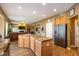 Open concept kitchen with island and stainless steel refrigerator flowing into the living room with fireplace at 6683 School Branch Dr, Brownsburg, IN 46112