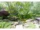 Backyard pond surrounded by lush landscaping and decorative rocks, creating a peaceful outdoor oasis at 7372 Fox Hollow Rdg, Zionsville, IN 46077