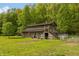 Unique barn-style house with a teal door, surrounded by lush greenery and a spacious yard at 7730 Bear Creek Rd, Morgantown, IN 46160