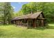 Charming cabin-style home featuring a covered porch, wood siding, and lush green lawn surrounded by trees at 7730 Bear Creek Rd, Morgantown, IN 46160