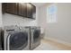 A laundry room featuring a front loading washer and dryer, window, and dark wood cabinets at 902 Racetime Rd, Westfield, IN 46074
