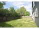 View of a spacious, grassy backyard with a wooden fence and mature trees providing privacy at 9613 W Stargazer Dr, Pendleton, IN 46064