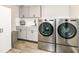 Modern laundry room with stainless steel washer and dryer, white cabinets, and wood floors at 9790 Summerlakes Dr, Carmel, IN 46032