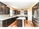 Well-equipped kitchen with dark cabinets, granite countertops, stainless steel appliances, and an island at 9860 Gallop Ln, Fishers, IN 46040
