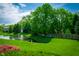 Lush backyard featuring a pond, green grass, mature trees, and partial fencing at 10075 Niagara Dr, Fishers, IN 46037