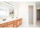 Bathroom featuring dual sinks, wood cabinets, a large mirror, and access to an additional area at 10075 Niagara Dr, Fishers, IN 46037