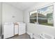 Bright laundry room featuring modern washer, dryer, and a large window with backyard view at 1043 N Beville Ave, Indianapolis, IN 46201